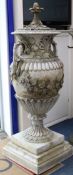 A pair of reconstituted stone Neo-Classical two handled campana shaped lidded urns, on plinths H.