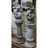 A pair of reconstituted stone columns, surmounted by putti seated on balls H.137cm