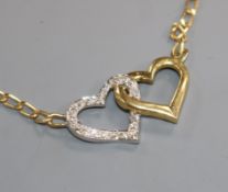 An 18ct gold and diamond set two colour twin hearts pendant necklace, approx. 37cm.