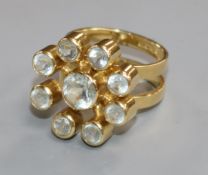 A modern 18ct gold and aquamarine stylised flower head cluster ring, size M/N.