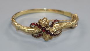 An early 20th century yellow metal and garnet set hinged bracelet.