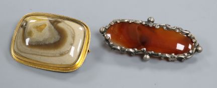 A yellow metal mounted agate brooch and a white metal and agate brooch.