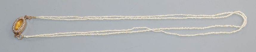 An early 20th century double strand seed pearl necklace with yellow metal, gem and seed pearl set