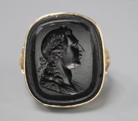 A yellow metal and black stone intaglio ring carved with the bust of a gentleman to sinister, size