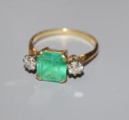 A yellow metal, emerald and diamond three stone ring, size R/S.