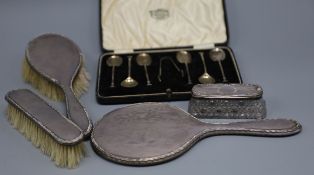 A set of six George V silver coffee spoons, a three piece dressing table set and a silver topped