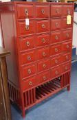 A red lacquer medicine cabinet, with twenty four drawers W.98cm