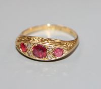 An early 20th century 18ct gold, three stone ruby and diamond chip dress ring, size M.
