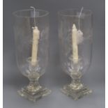 A pair of glass storm candle holders, each engraved with foliate band on stepped square base, H