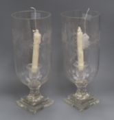 A pair of glass storm candle holders, each engraved with foliate band on stepped square base, H