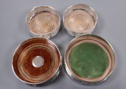 A pair of modern silver wine coasters and two other silver wine coasters.