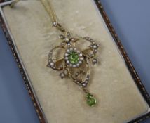 An Edwardian 9ct, peridot and seed pearl set drop pendant on a yellow metal chain, pendant 40mm.