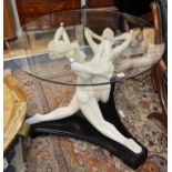 A circular plate glass topped table, the base formed as three nude female figures, in cream resin