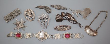 A collection of silver and white metal brooches, bangles etc.