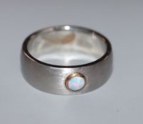 A modern brushed steel? band with single stone collet set white opal, size Z.