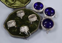 A set of three Victorian embossed silver cauldron salts with blue glass liners and a set of four