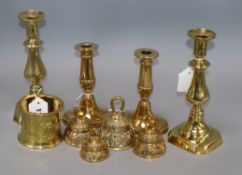 Two pairs of brass candlesticks, four embossed brass table bells of varying sizes and an Art Nouveau