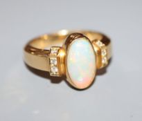 A modern 750 yellow metal, white opal and diamond set dress ring, size L/M.