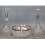 A pair of silver collared cut glass decanters and a similar bowl