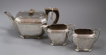 A matched silver three-piece tea service, of shaped rectangular form with reeded corners, handles