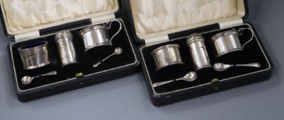 A pair of cased 1930's three piece silver condiment sets by Harrod's Ltd.