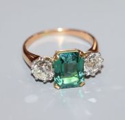 A yellow metal, green tourmaline and diamond set three stone ring, size M/N.