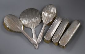 A George V silver mounted five piece mirror and brush set and one other silver mounted brush.