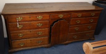 A mid 18th century oak dresser, fitted nine drawers surrounding a cupboard W.206cm