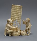 A 19th century Japanese okimono of two figures washing a screen, with a mouse running upwards