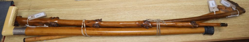 A fruitwood walking cane carved with multiple fox and dog masks and three other walking canes,