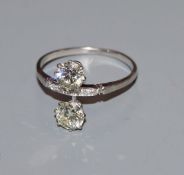 A mid 20th century white metal and two stone diamond crossover ring, with diamond set shank, total