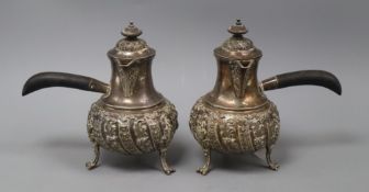 A pair of late Victorian embossed silver chocolate pots, of bellied form with hinged covers and