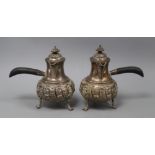 A pair of late Victorian embossed silver chocolate pots, of bellied form with hinged covers and