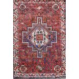 A Shiraz design red ground rug, with central polygon in a field of flower heads and three row