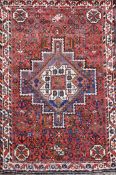 A Shiraz design red ground rug, with central polygon in a field of flower heads and three row