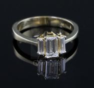 A modern 750 gold and graduated baguette cut diamond three stone ring, size Q/R.