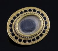 A Victorian gold and black enamel oval mourning brooch, with hair beneath a glazed panel and