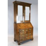 A mid 18th century walnut bureau bookcase, with two mirrored doors enclosing shelves, over a fall