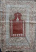 A Turkish Kum Kapri silk red ground hanging prayer rug, with central mihrab and three row