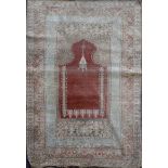 A Turkish Kum Kapri silk red ground hanging prayer rug, with central mihrab and three row