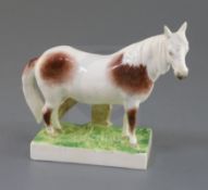 A previously undocumented Rockingham porcelain figure of a skewbald pony, c.1830, standing on a