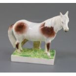 A previously undocumented Rockingham porcelain figure of a skewbald pony, c.1830, standing on a