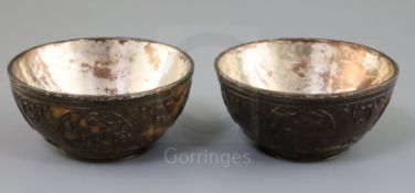 A pair of Chinese coconut bowls, 18th century, each carved in relief with flower roundels and