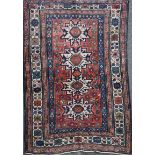 A Caucasian red ground rug, with four central stylised star motifs and four row geometric border,