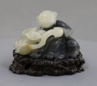 A Chinese pale celadon and grey jade figure of a seated boy, holding a gourd and bat to one side