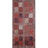 A Turkoman red ground rug, with field of thirty two square panels containing geometric motifs and