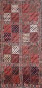 A Turkoman red ground rug, with field of thirty two square panels containing geometric motifs and