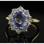 A modern 18ct gold, sapphire and diamond oval cluster ring, the pale blue sapphire bordered with ten