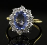 A modern 18ct gold, sapphire and diamond oval cluster ring, the pale blue sapphire bordered with ten