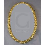 An early 19th century giltwood and gesso oval wall mirror, with laurel leaf frame, W.1ft 10in. H.2ft